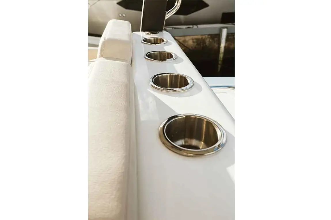 A close-up of a boat's white armrest with polished cup holders, showcasing a stylish and functional marine design.